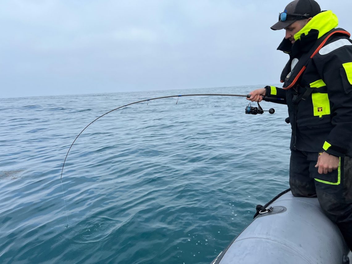 pêcheur avec canne à pèche dans la mains et poisson au bout de la ligne