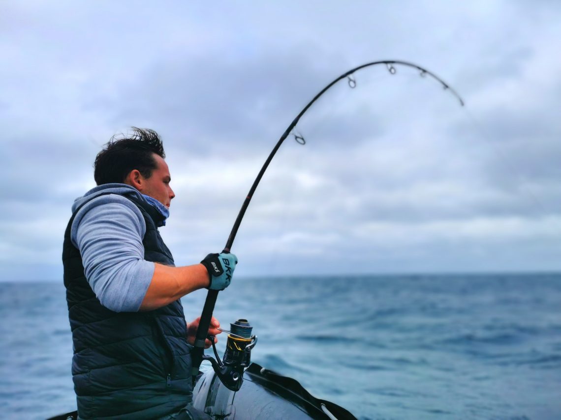 pêcheur avec canne dans les mains en train de combattre un thon rouge.