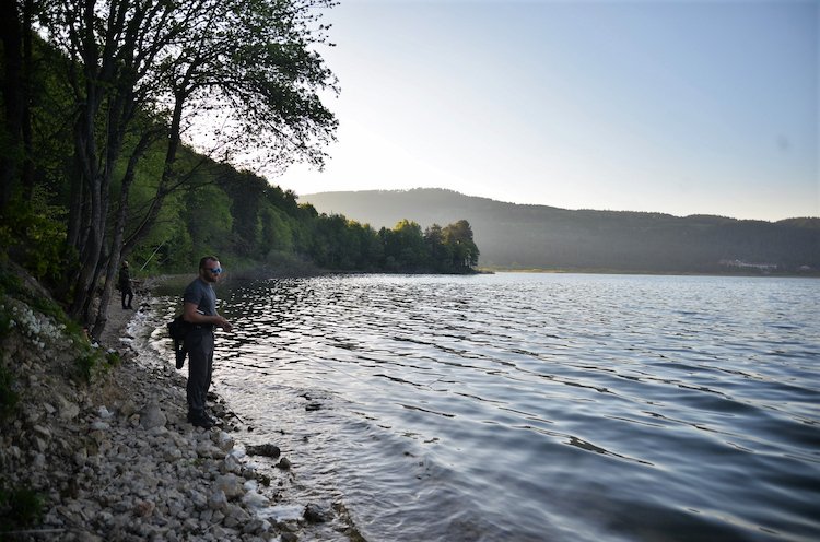 pêcheur sur la berge d'un grand lac naturel